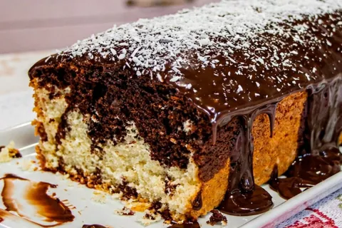 Bolo mesclado de coco com chocolate e cobertura cremosa, que